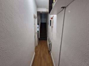 een hal met witte muren en een trap bij City Budget Guesthouse in Londen