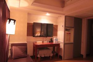a room with a desk with a television on the wall at The Moon Hotel in Taipei