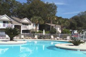 a large swimming pool with chairs and a fence at A12 1 bedroom with 2 beds and great view of pool, upstairs, new floors, two full size beds in Saint Simons Island