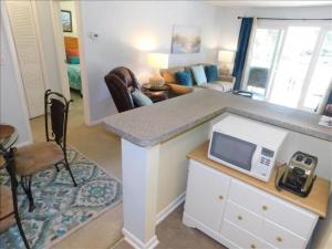 a kitchen with a counter with a microwave and a living room at A12 1 bedroom with 2 beds and great view of pool, upstairs, new floors, two full size beds in Saint Simons Island
