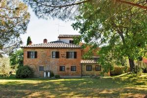 una vieja casa de ladrillo con árboles delante de ella en Agriturismo Podere Caggiolo - Swimming Pool & Air Conditioning en Marciano