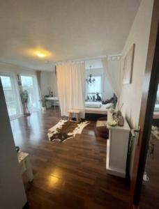 a living room with a wooden floor and white curtains at Complete Apartment peacefully situated near the Airport Nürnberg in Nürnberg