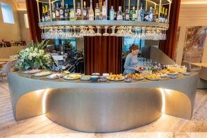 Dos Reis by The Beautique Hotels في لشبونة: امرأة تقف وراء بار مع لوحات من الطعام