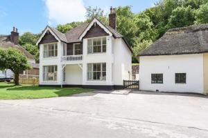 a large white house with a thatched roof at Little Maltings in Milton Abbas