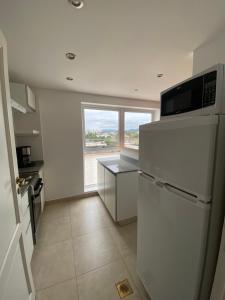 cocina con nevera blanca y ventana en Hermoso departamento de 2 habitaciones, en Salta Capital en Salta