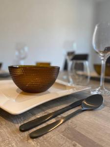 uma mesa de madeira com uma tigela e um prato com uma colher em Ô’pti Cavens em Malmedy