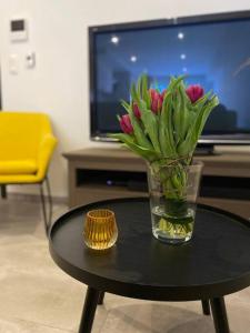 eine Vase mit Blumen auf einem Tisch im Wohnzimmer in der Unterkunft Ô’pti Cavens in Malmedy