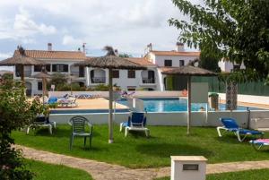a yard with chairs and umbrellas and a swimming pool at Siestamar in Cala en Porter