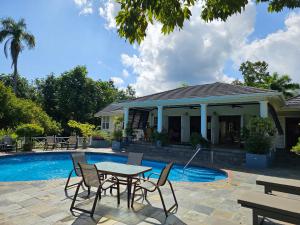 een patio met een tafel en stoelen naast een zwembad bij Spicy Hill Villa in Port Antonio