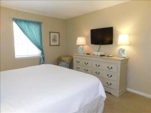 a bedroom with a white bed and a flat screen tv at J15 lovely village area condo sleeps 6 comfy very nicely furnished screened in porch in Mallory Park +15 photos