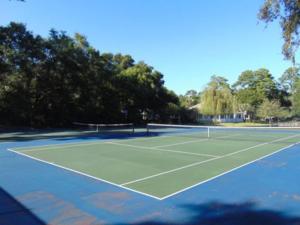 a tennis court with trees in the background at H5 close to the front pool and clubhouse downstairs by lake in Mallory Park