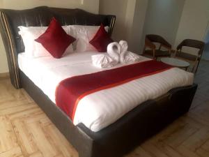 a large bed with red and white blankets and pillows at Wilsen Hotel Nansana in Kampala