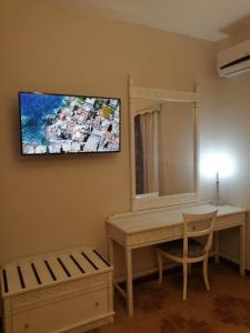 a room with a desk with a mirror and a television on the wall at Dionisia apartments 8 in Kos