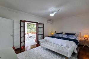 a bedroom with a white bed and a white couch at Casa com piscina e churrasqueira no Guarujá in Guarujá