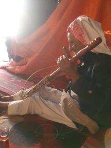 a man playing a flute while sitting on the floor at Bedouin experiences in Aqaba