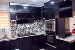 a kitchen with black cabinets and a sink and a microwave at Modern Luxury Home W/ 24H Power Wi-Fi & Security in Abuja