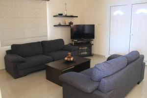 sala de estar con 2 sofás y TV en Maricosta Villas, en Protaras
