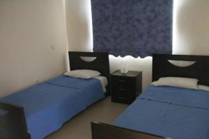 two beds in a room with blue sheets at Maricosta Villas in Protaras