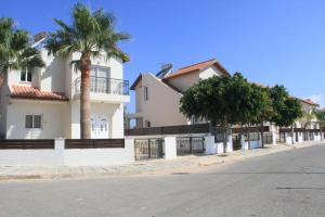 una fila de casas en una calle con palmeras en Maricosta Villas, en Protaras