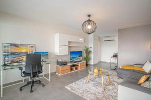 a living room with a couch and a desk at Appartement standing vue sur mer des Caraïbes in Fort-de-France