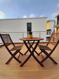 uma mesa de madeira e 2 cadeiras numa varanda em Beautiful Home - 2 Double Rooms em Acra