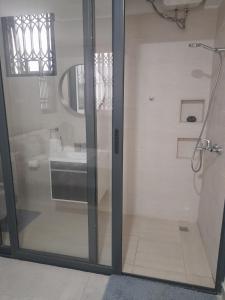 a glass shower door with a sink in a bathroom at Beautiful Home - 2 Double Rooms in Accra