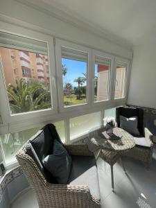 een woonkamer met stoelen en een tafel en ramen bij Mango / Estudio con piscina!!! in Torrox Costa