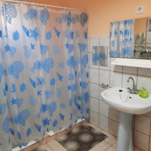 a bathroom with a sink and a shower curtain at Kisfaludy Vendégház in Abádszalók