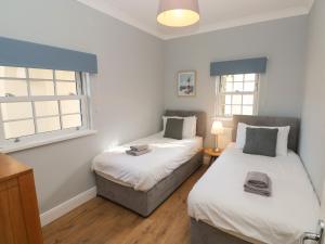 two beds in a room with two windows at Harbour Beach at The Hideaway in Tenby