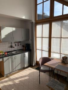 cocina con armarios blancos, mesa y ventanas en Ferienland Sonnenwald Fewo 46 und Studio 50 in Schöfweg Bayerischer Wald, en Schöfweg