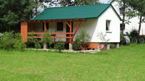 une petite maison blanche avec un toit vert dans l'établissement Agroturystyka u Wioli i Irka, domek u Elki , spływy kajakowe, à Karsin