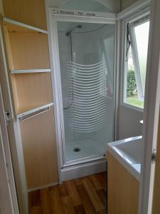 y baño con ducha acristalada y lavamanos. en Mobilhome proche du Puy du Fou en La Boissière-de-Montaigu