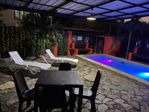 un patio con sillas y una mesa junto a la piscina en Cabaña Don Tobo Jarabacoa RD, en Jarabacoa