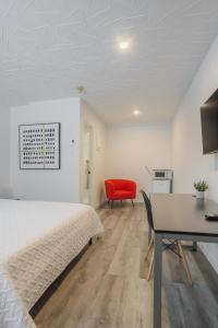 a bedroom with a bed and a desk and a red chair at Motel Champlain in Brossard