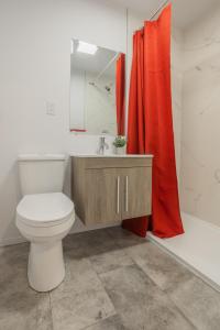 uma casa de banho com um WC e uma cortina de chuveiro vermelha. em Motel Champlain em Brossard