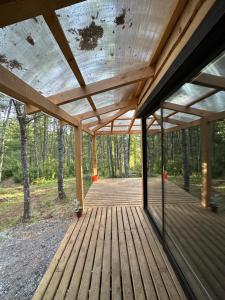 a wooden deck with a roof in the woods at Cabaña Chucao, Nativo Lodge in Curacautín