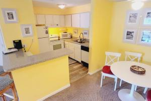 een keuken met gele muren en een tafel en stoelen bij A16 Ocean Walk 1 bdrm sleeps 5 next to pool upstairs unit two full size beds full kitchen in Saint Simons Island