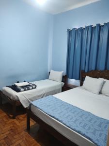 two beds in a room with blue walls and blue curtains at Hotel Mirante da Serra in Ouro Branco