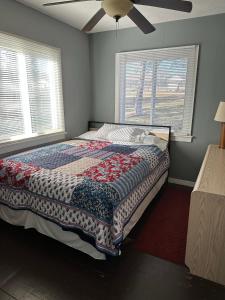 a bed in a bedroom with two windows and a ceiling fan at Wagon Wheel Resort Lake Norfork in Gamaliel