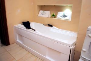 eine weiße Badewanne im Bad mit Spiegel in der Unterkunft Modern Luxury Home W/ 24H Power Wi-Fi & Security in Abuja