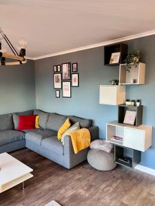 a living room with a gray couch and blue walls at Apartment of Love in Olecko