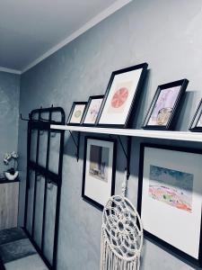 a shelf with pictures and a chair on a wall at Apartment of Love in Olecko