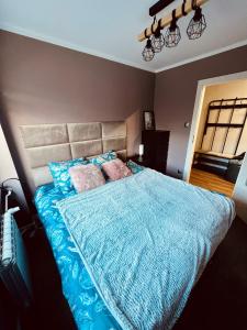 a bedroom with a bed with a blue comforter and pillows at Apartment of Love in Olecko