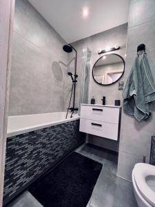 a bathroom with a tub and a sink and a mirror at Apartment of Love in Olecko