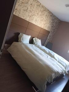 um quarto com uma cama grande com lençóis brancos e almofadas em Appartement Gauche avec balcon em Hargarten-aux-Mines