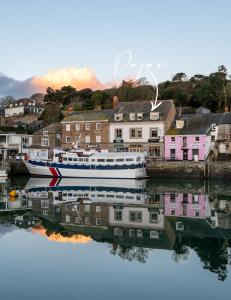 a boat is docked in the water next to houses at Padstow Escapes - Pajar Luxury Penthouse Apartment in Padstow