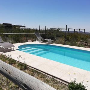 una piscina con 2 sillas de césped en Aguara House Pedemonte Mendoza en Mendoza