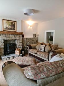 a living room with couches and a stone fireplace at Stunning riverside cottage in central location in Donegal