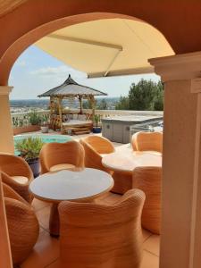 eine Terrasse mit Tischen, Stühlen und einem Pavillon in der Unterkunft Les Collines d'Ugernum in Beaucaire