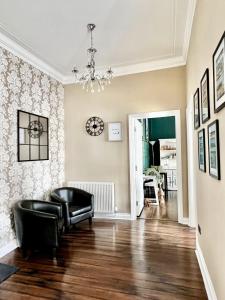 a living room with a black chair and a clock on the wall at Devon House Guest House in Paignton